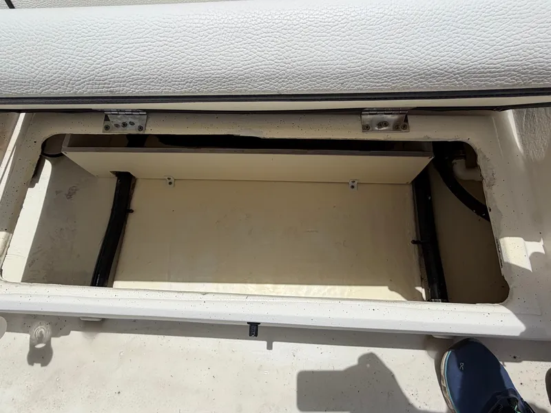 Slide: The Image of An open storage compartment on a 2016 Cape Craft 180cc boat, with white upholstery above. - 26