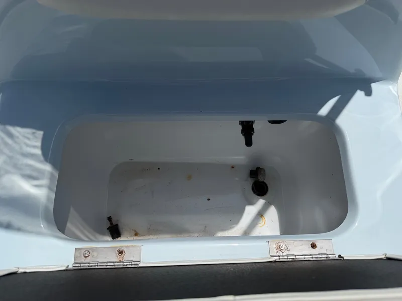 Slide: The Image of An open storage compartment on a 2023 Excel 203 Bay Pro boat, with visible hinges and drain. - 21