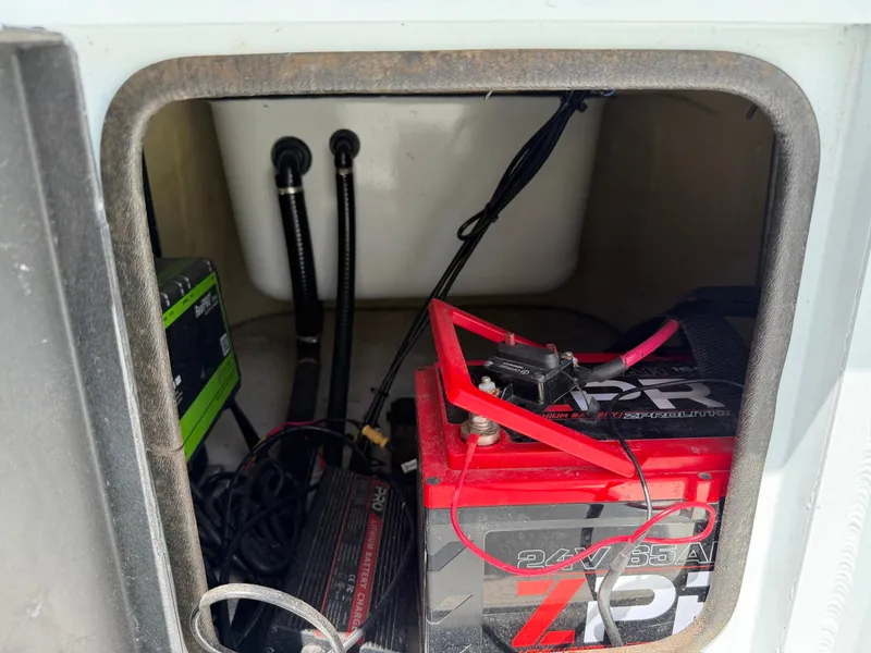 Slide: The Image of A battery compartment with a red battery and cables inside a boat. - 24