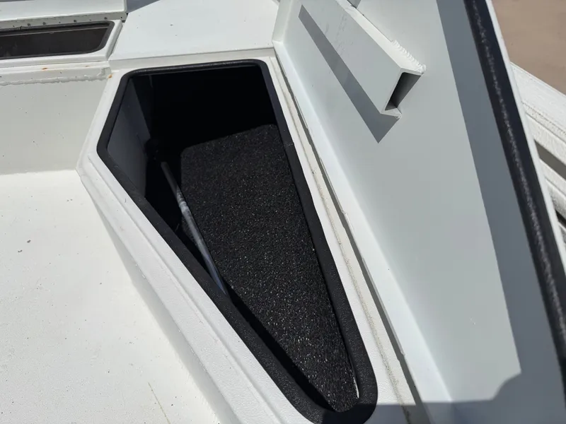 Slide: The Image of An open storage compartment on a 2023 Excel 203 Bay Pro boat, featuring black interior lining. - 16