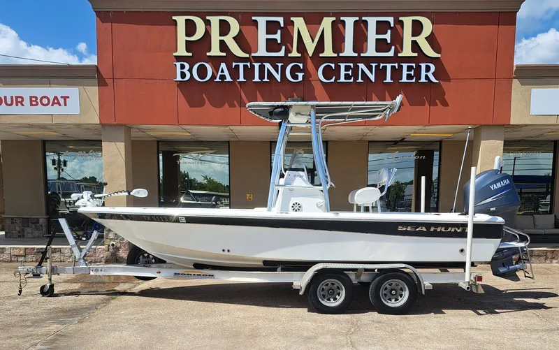 The Image of A white 2011 Sea Hunt XP21 boat on a trailer in front of a boating center. - 1