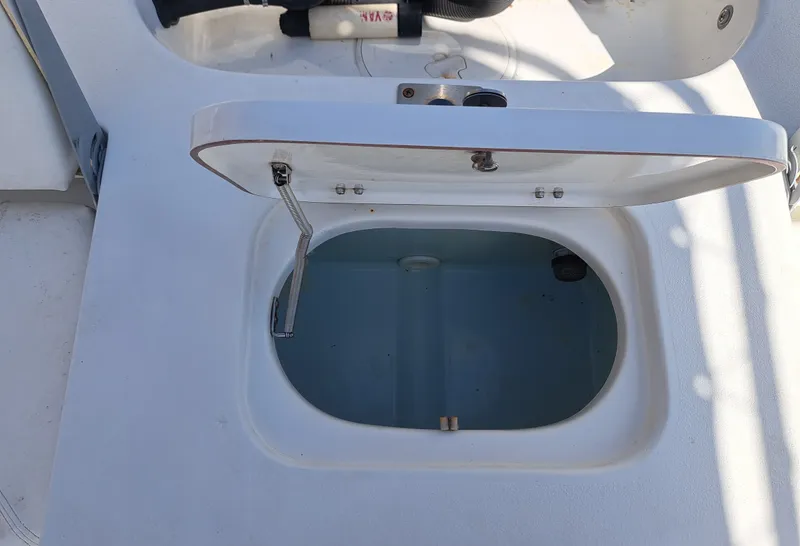 Slide: The Image of An open storage compartment on a 2011 Sea Hunt XP21 boat, featuring a lever for opening. - 18