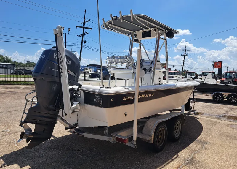 Slide: The Image of A 2011 Sea Hunt XP21 boat on a trailer, featuring a Yamaha outboard motor and T-top. - 10