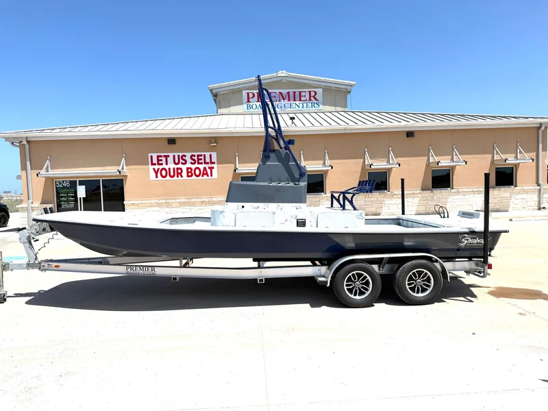 The Image of A Shoalwater 23 CAT RSD boat on a trailer in front of a boat center building. - 1