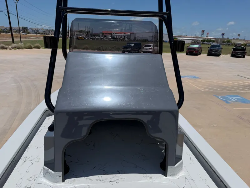 Slide: The Image of A 2027 Shoalwater 23' Catamaran with a gray deck and black T-top, parked in a lot. - 18