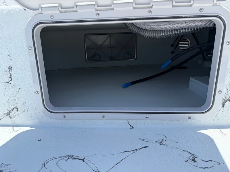 Slide: The Image of An open storage compartment on a 2027 Shoalwater 23' Catamaran, showing cables and piping. - 14