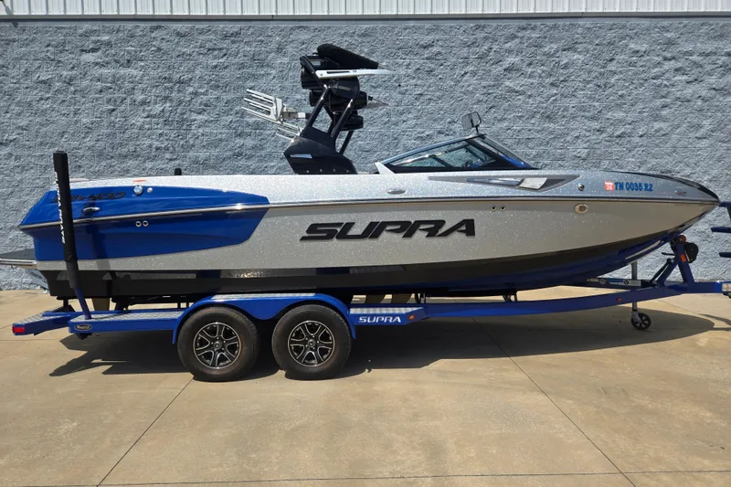 The Image of 2017 Supra SG 400-550 boat on trailer, blue and silver design, parked outdoors. - 1