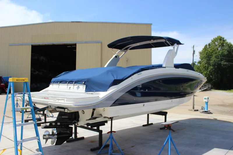 Slide: The Image of 2019 Sea Ray SDX 290 boat on stands, covered, near a large warehouse. - 6
