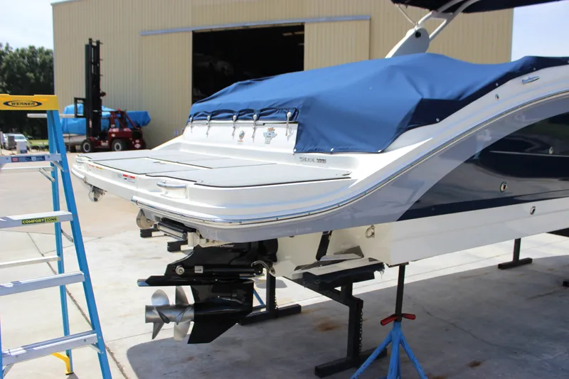 Slide: The Image of 2019 Sea Ray SDX 290 boat on stand, covered, with visible propeller and ladder nearby. - 5