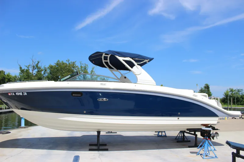 Slide: The Image of 2019 Sea Ray SDX 290 boat on stands, blue and white design, clear sky background. - 18