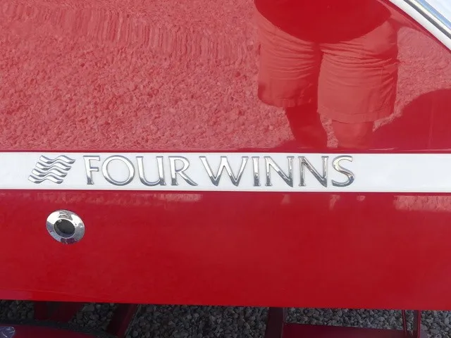 Slide: The Image of Close-up of a red Four Winns boat hull with logo. - 30