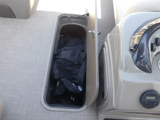 Slide: The Image of An open storage compartment on a Sun Tracker SportFish 22 DLX boat reveals black covers. - 39
