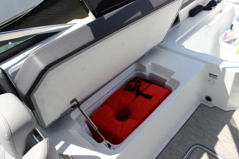 Slide: The Image of 2024 Cobalt R6 Outboard boat storage compartment with red life jacket inside. - 38