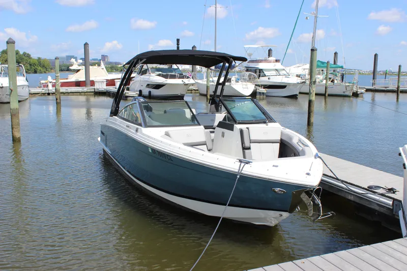 Slide: The Image of 2024 Cobalt R6 Outboard boat docked in a marina under a clear blue sky. - 1