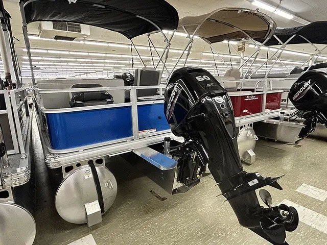 Slide: The Image of A 2027 Sun Tracker Bass Buggy 18 DLX with a Mercury outboard motor in a showroom. - 15