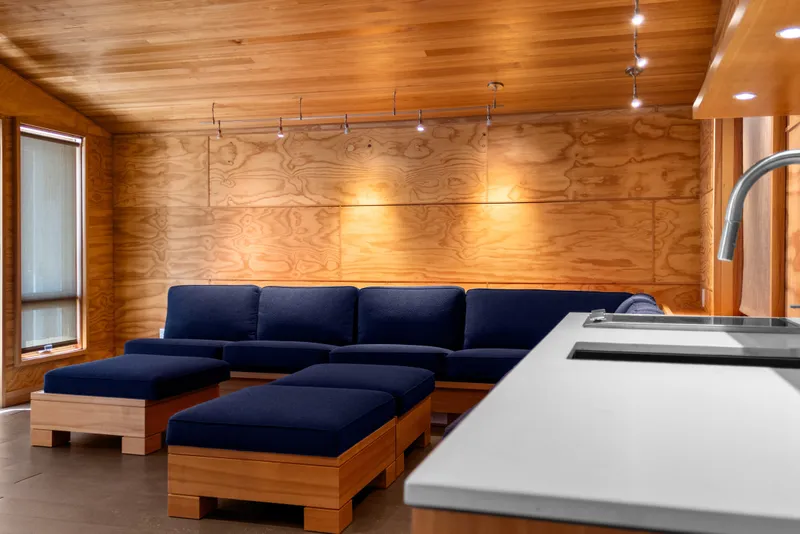 Slide: The Image of Modern boathouse interior with wooden walls, blue seating, and sleek kitchen area, 1969 design. - 65