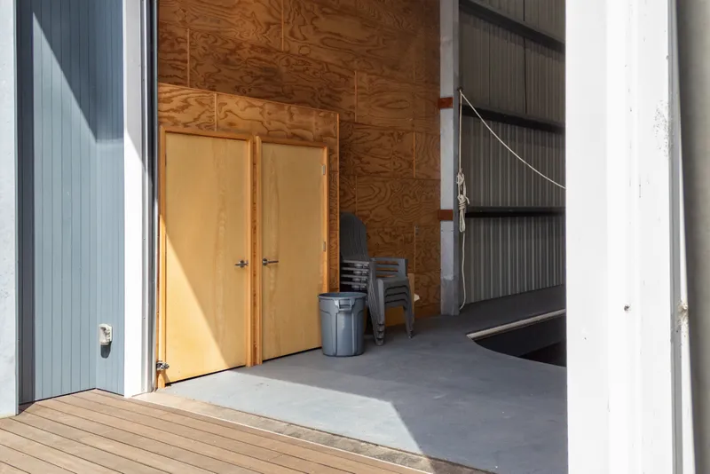 Slide: The Image of Interior of a 1969 custom all-steel boathouse with wooden doors and stacked chairs. - 11