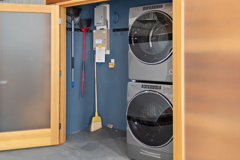 Slide: The Image of Laundry area with stacked washer and dryer, cleaning tools, and wooden sliding door. - 33
