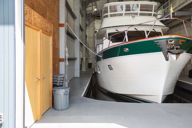 Slide: The Image of Custom All Steel Boathouse from 1969 housing a large white and green boat indoors. - 8