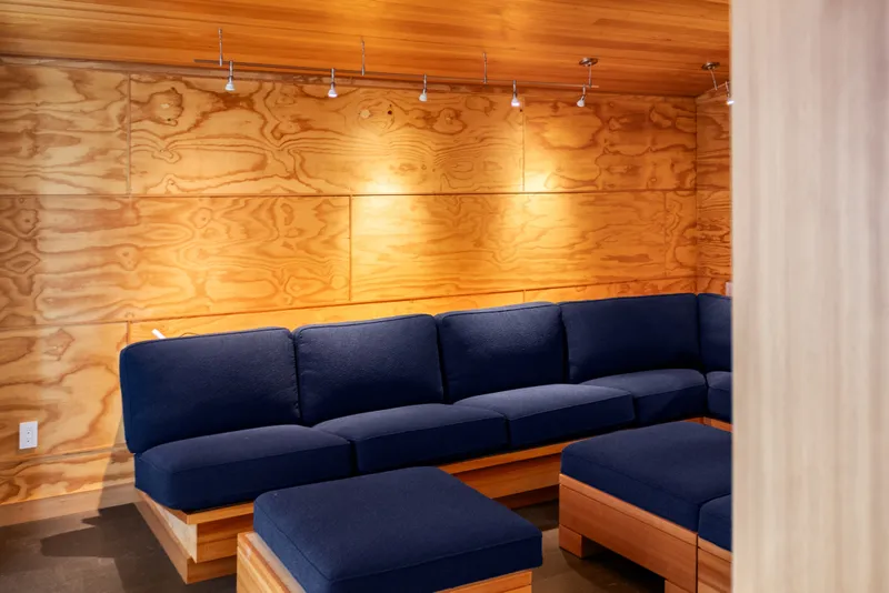 Slide: The Image of Modern boathouse interior with blue sectional sofa, wooden walls, and ceiling lighting, 1969 design. - 60