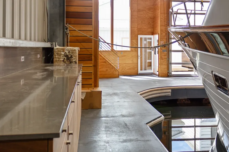 Slide: The Image of Interior of a 1969 Custom All Steel Boathouse with docked boat and wooden accents. - 29