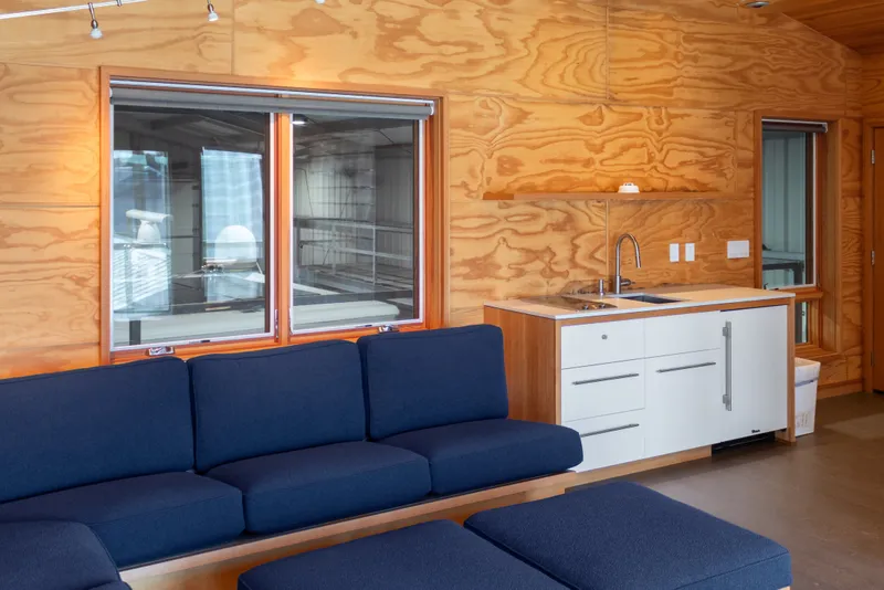 Slide: The Image of Modern boathouse interior with wood paneling, blue sofa, and compact kitchenette, 1969 design. - 62