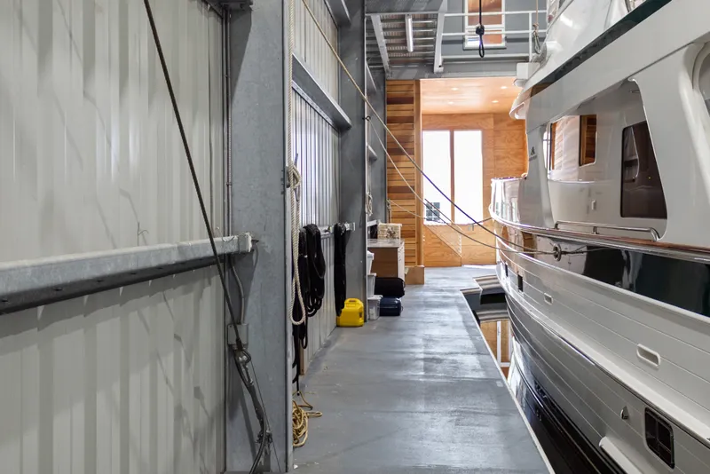 Slide: The Image of Interior of a 1969 Custom All Steel Boathouse with docked yacht and storage items. - 25