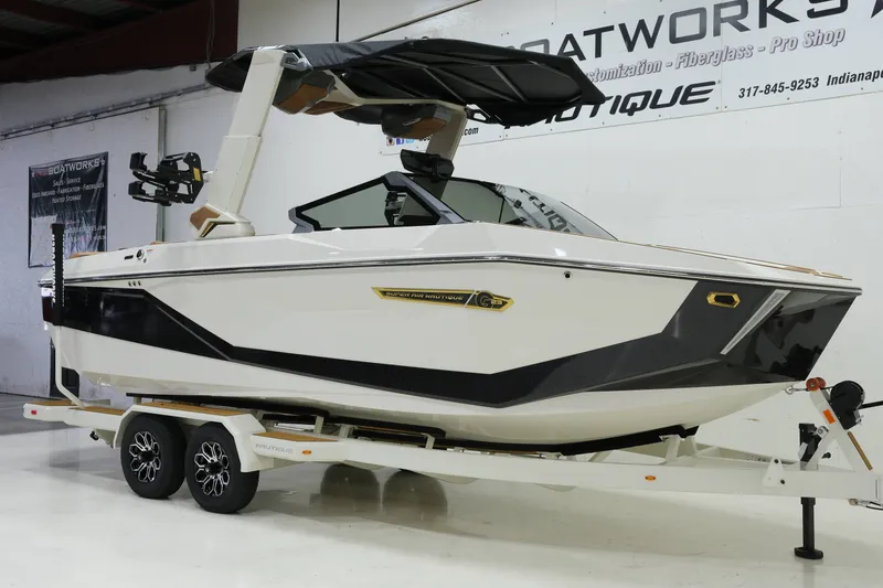 Slide: The Image of A white 2027 Nautique G23 boat on a trailer in a showroom setting. - 2