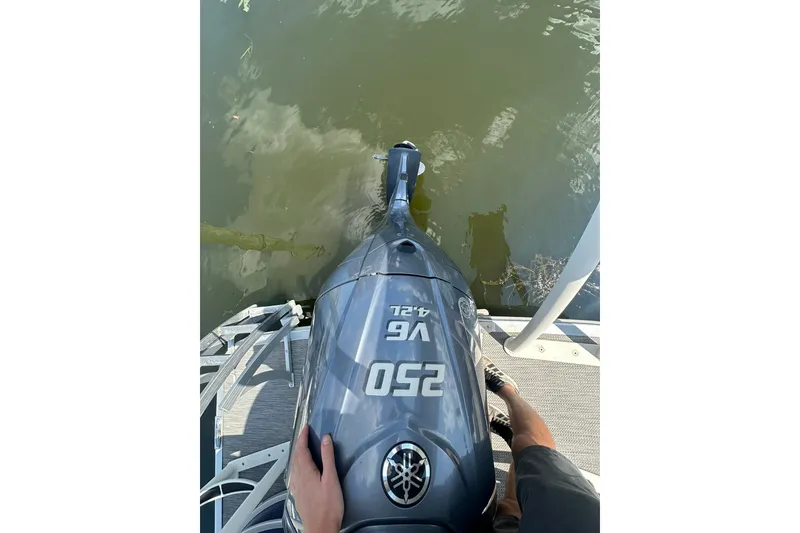 Slide: The Image of Outboard motor on a 2021 Bennington L Bowrider 25 Swingback, docked by the water. - 5