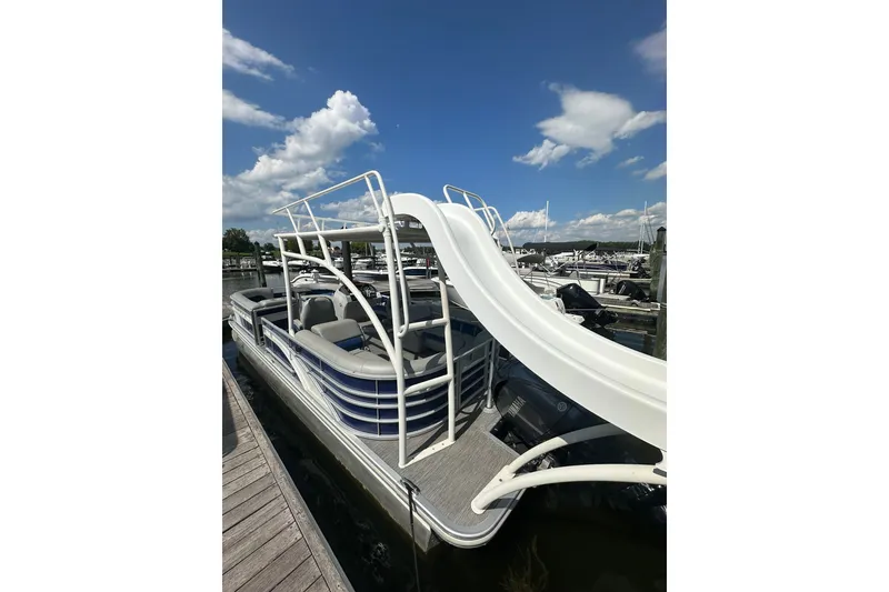 Slide: The Image of 2021 Bennington L Bowrider 25 Swingback pontoon boat with slide, docked under blue sky. - 3