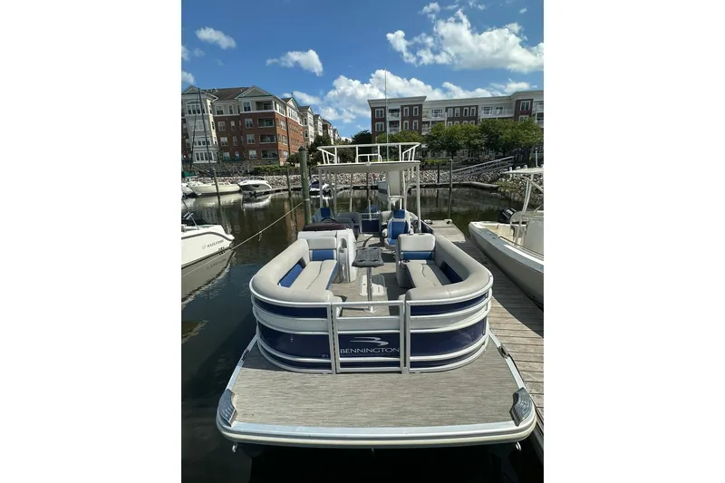 Slide: The Image of 2021 Bennington L Bowrider 25 Swingback pontoon boat docked at marina. - 2