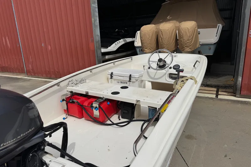 The Image of 2012 Boston Whaler 130 Super Sport boat in storage, featuring steering wheel and outboard motor. - 1