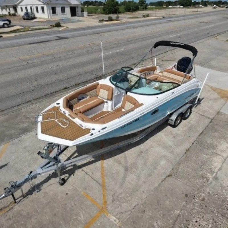 The Image of 2025 NauticStar 243 DC Deck boat on trailer, parked in urban area. - 0