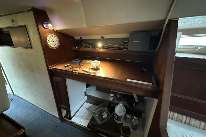 Slide: The Image of 1980 Morgan 415 Ketch interior with wooden desk, clock, and storage shelves. - 13