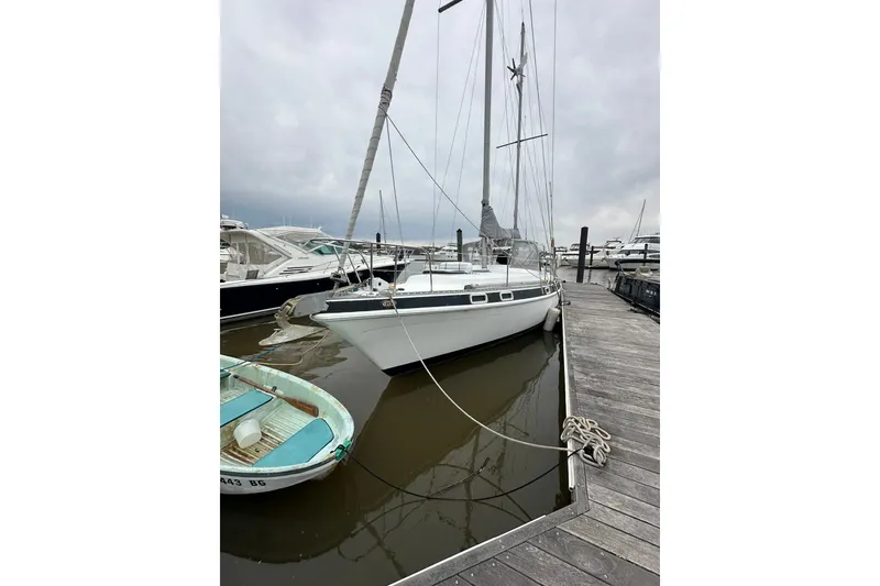 Slide: The Image of 1980 Morgan 415 Ketch sailboat docked at marina, overcast sky, calm waters. - 2