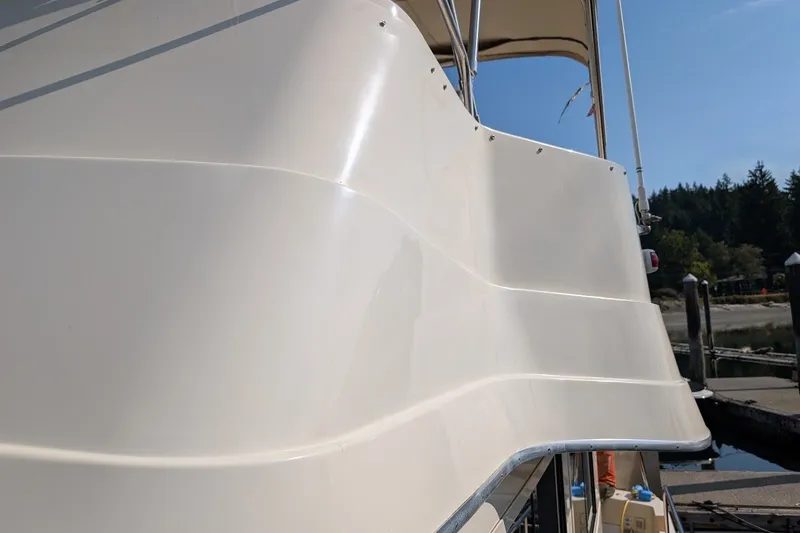 Slide: The Image of 2008 Mainship 34 Trawler side view at dock, showcasing sleek design and structure. - 44