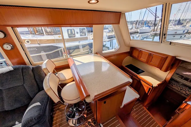 Slide: The Image of Interior of 2008 Mainship 34 Trawler with seating, table, and marina view. - 18