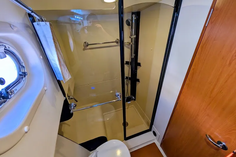 Slide: The Image of Bathroom interior of 2008 Mainship 34 Trawler, featuring shower and porthole window. - 29