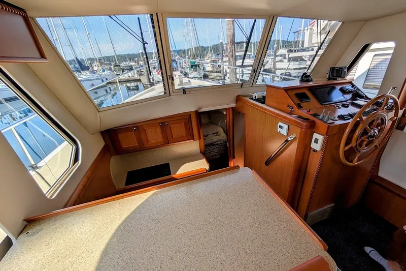 Slide: The Image of 2008 Mainship 34 Trawler interior with helm, wooden cabinetry, and marina view. - 19