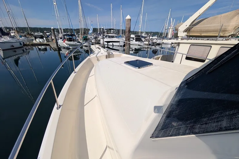 Slide: The Image of 2008 Mainship 34 Trawler docked at marina, surrounded by sailboats under clear sky. - 13