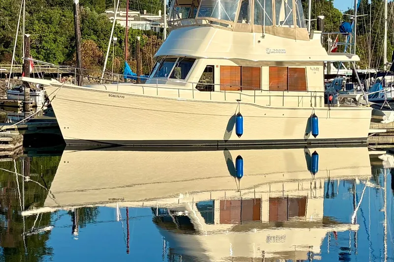 Slide: The Image of 2008 Mainship 34 Trawler docked, reflecting on calm water in a marina setting. - 54