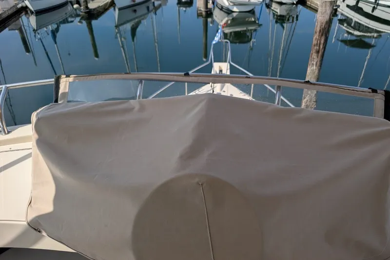 Slide: The Image of 2008 Mainship 34 Trawler at marina, covered helm, calm water reflections. - 36