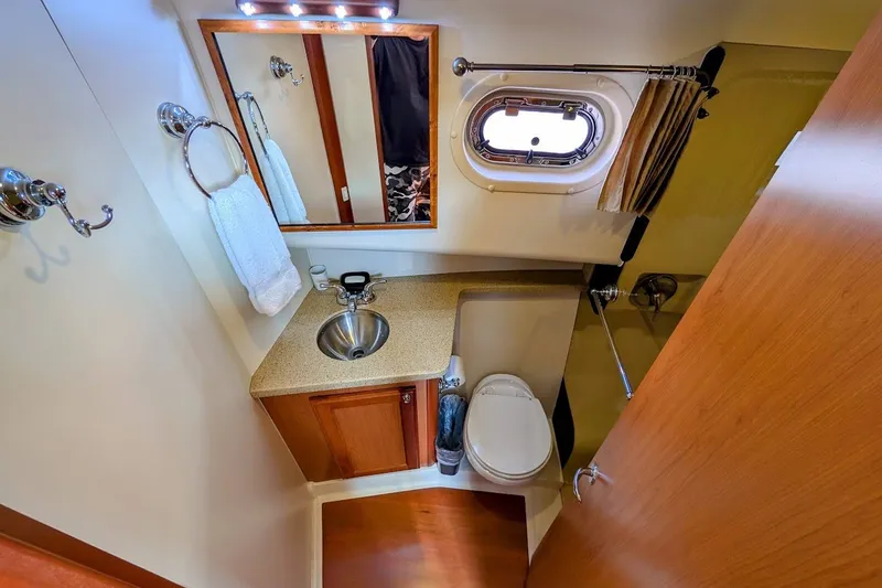 Slide: The Image of Bathroom interior of 2008 Mainship 34 Trawler with sink, toilet, and porthole window. - 28