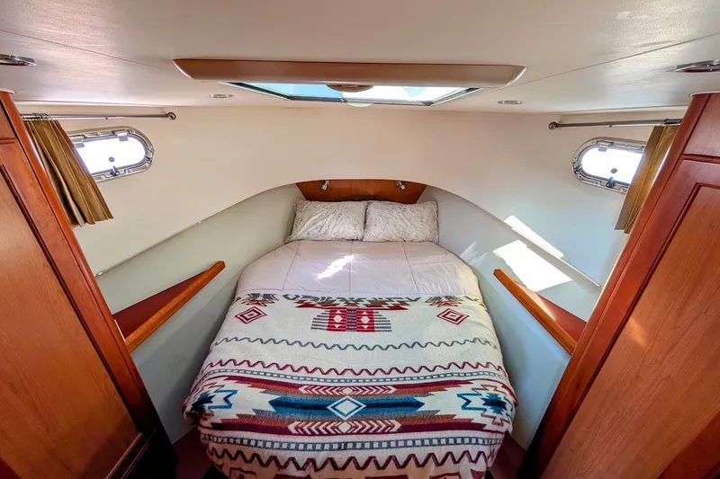 Slide: The Image of Cozy cabin interior of 2008 Mainship 34 Trawler with patterned bedding and natural light. - 25