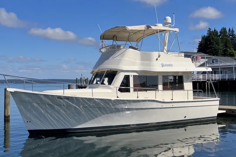 The Image of 2008 Mainship 34 Trawler docked on calm water under a clear sky. - 0