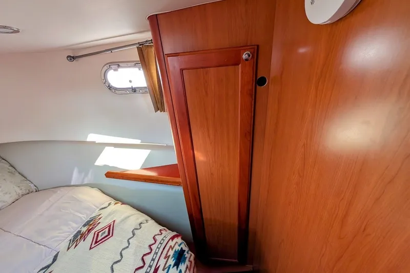 Slide: The Image of Interior cabin of 2008 Mainship 34 Trawler with wooden cabinetry and cozy bedding. - 26