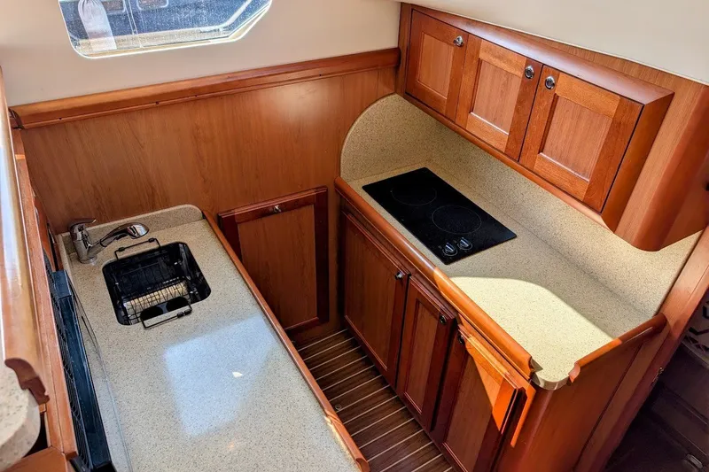 Slide: The Image of 2008 Mainship 34 Trawler kitchen with wooden cabinets, sink, and stovetop. - 20