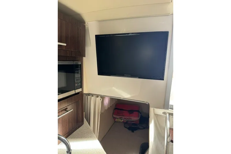 Slide: The Image of Interior of 2018 Regal 28 Express boat with TV, microwave, and life jackets. - 15
