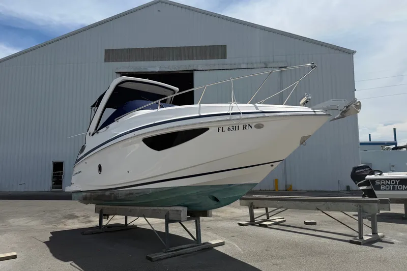 The Image of 2018 Regal 28 Express boat on a stand outside a large warehouse. - 0