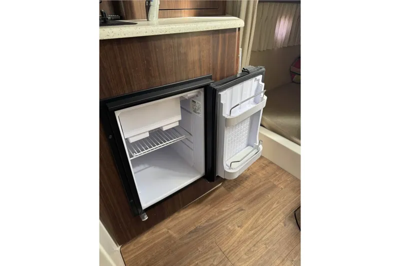 Slide: The Image of Open mini fridge inside 2018 Regal 28 Express boat cabin, showcasing interior storage space. - 13